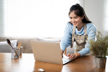 Young asian women working at home, using laptop computer in kitchen room.