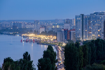 Fototapeta premium Volga River embankment in Saratov, Russia. The view from the height. Evening landscape. Burning street lights.