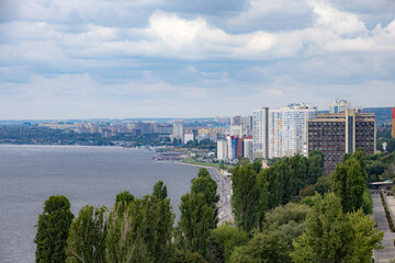 Volga River embankment in Saratov, Russia. Clouds in the sky. Trees and various buildings.