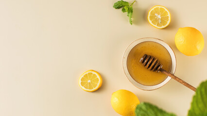Honey with fresh lemons and fresh mint leaves on beige. Copy space
