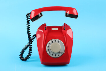 Red telephone with handset on light blue background