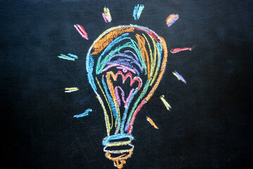 Creativity and new ideas. Lightbulb drawn on a chalkboard with colorful chalk.