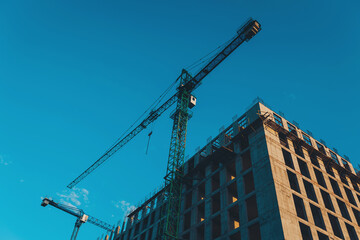 building around crane construction equipment. Construction of apartment building from concrete,...