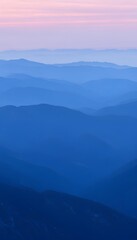 Obraz premium Serene mountain landscape at dusk with layers of blue-hued ridges captured under a soft pastel sky