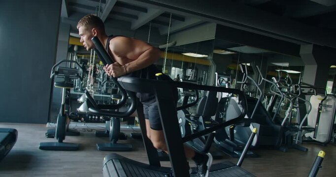 An athletic man in sportswear intensely running on a treadmill in a well-equipped, contemporary gym. Focus on fitness and endurance. Young Man Focused on Running in a Modern Gym Setting