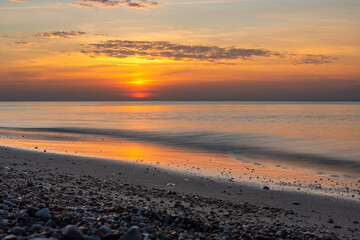 Sandy beach with pebbles of Baltic Sea on Curonian Spit at sunset. Kaliningrad region. Russia