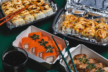Sushi in delivery boxes on the table and chopsticks