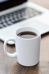 Coffee Mug on Desk with Blurred Laptop Background.