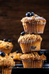 Blueberry muffins placed one on top of the other are sprinkled with powdered sugar on top