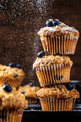 Blueberry muffins placed one on top of the other are sprinkled with powdered sugar on top