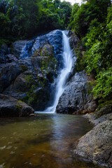Waterfall in deep tropical rainforest with green rainy tree