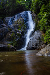 Obraz premium Waterfall in deep tropical rainforest with green rainy tree