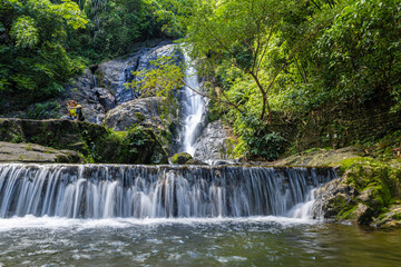 Obraz premium Waterfall in deep tropical rainforest with green rainy tree