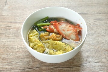 Chinese dumpling topping slice red barbecue pork and cabbage in clear soup on bowl