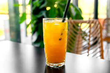Orange fresh cool juice cocktail in glass on table in cafe,bar. Tropical drink for summer party.refreshing drink or beverage with ice on light interior background with copy space