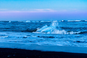 Summer midnight sky over Diamond Beach in Iceland with icebergs in the cold water