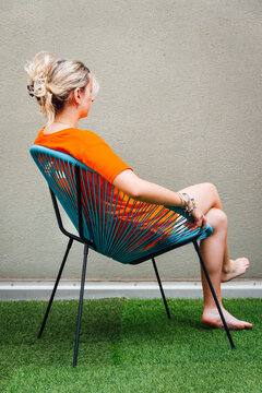 Femme v&ecirc;tue de orange assise sur un fauteuil bleue. Jeune femme en orange sur un si&egrave;ge bleu. Portrait. tronie