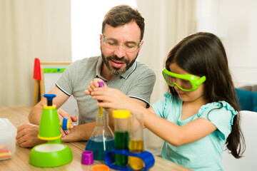 Father and daughter using safety goggles and conducting chemistry experiments during homeschooling