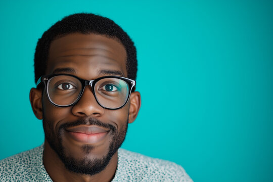 Handsome young African American guy with round lens glasses. Blue background. Smiling. 