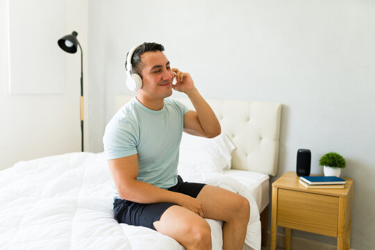 Relaxed man relaxes in his pajamas while listening to his favorite playlist on headphones
