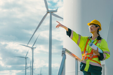 female engineer working outdoor with safety at wind turbines clean energy power station background,...