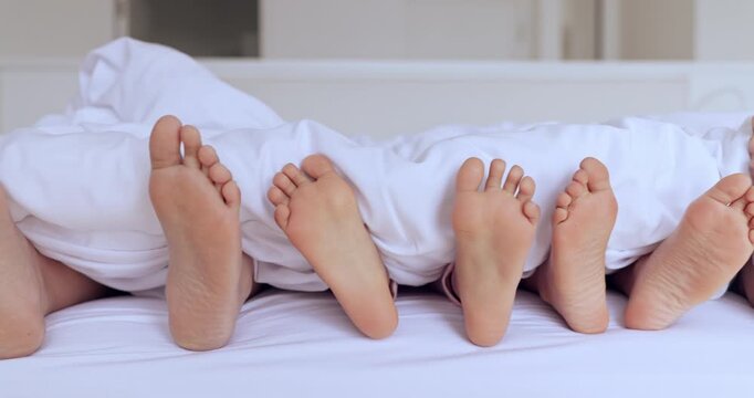 Family, bed and feet with sheet, sleep and together in home with rest, hospitality and comfort with bonding. People, children and bedroom with toes, blanket and sole to relax, holiday or vacation