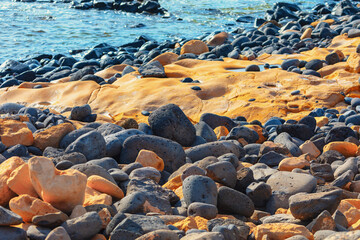 Rocky beach with ocean in the background. Rocks are of various sizes and colors, creating a natural and rugged landscape. Concept of tranquility and serenity, as the rocks