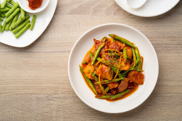 Stir fried sliced pork and red curry paste with sting bean in white plate,pad prik gaeng.Top view