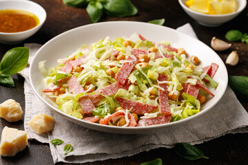 La Scala Salad with romaine lettuce, salami, mozzarella cheese and chickpeas in white plate.