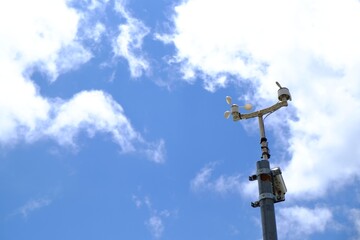 Anemometer on pole against blue sky, space for text