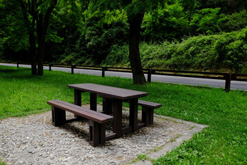 Fototapeta premium Empty wooden picnic table with benches in park on sunny day