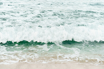 The waves of the emerald sea towards the beach that looks like a painting