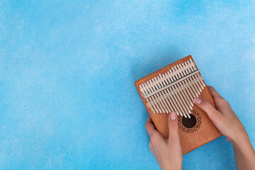 Female hands with a kalimba on a blue background