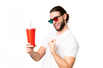 Young handsome man holding soda while watching a 3D movie over isolated chroma key background celebrating a victory