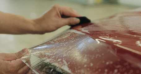 professional applying protective film to the red car
