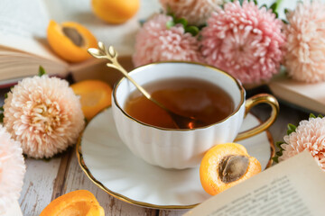 A cup of tea, ripe apricots and cakes on the table, aster flowers. August.