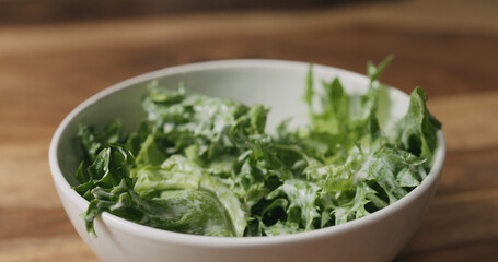 frillis salad leaves falling into white bowl