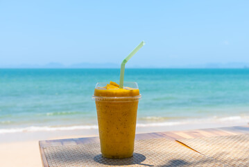 Smoothie made from fresh mango fruits and passion fruits with sea and sky background.
