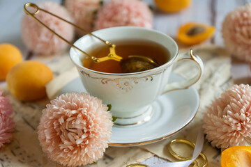 A cup of tea, ripe apricots and cakes on the table, aster flowers. August.