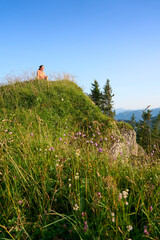 pretty senior woman hiking in warm dawn sunlight and enjoying the spectacular view over the Allgau...