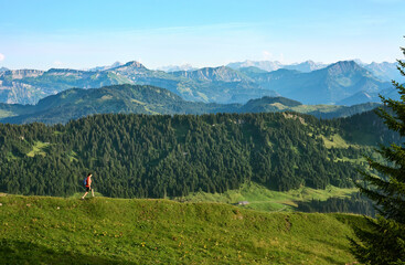 pretty senior woman hiking in warm dawn sunlight and enjoying the spectacular view over the Allgau...