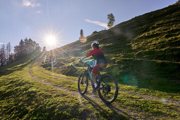 Fototapeta premium pretty senior woman riding her electric mountain bike and enjoying the spectacular view over the Allgau alps below the Nagelfluh mountain chain next to Steibis, Bavaria, Germany 