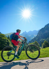 Fototapeta premium active senior woman riding her electric mountain bike in the spectacular Rappenalpen Valley south of Oberstdorf in the Allgaeu High Alps, Bavaria, Germany
