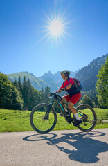 Obraz premium active senior woman riding her electric mountain bike in the spectacular Rappenalpen Valley south of Oberstdorf in the Allgaeu High Alps, Bavaria, Germany