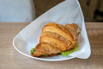 Croissant with ham, cheese and green on a plate.