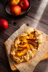 Homemade nectarine galette on dark wooden background, close up, place for text, top view