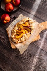 Homemade nectarine galette on dark wooden background, close up, place for text, top view