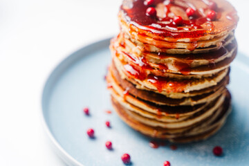 A stack of traditional American pancakes with raspberry and lingonberry sauce with berries on a...