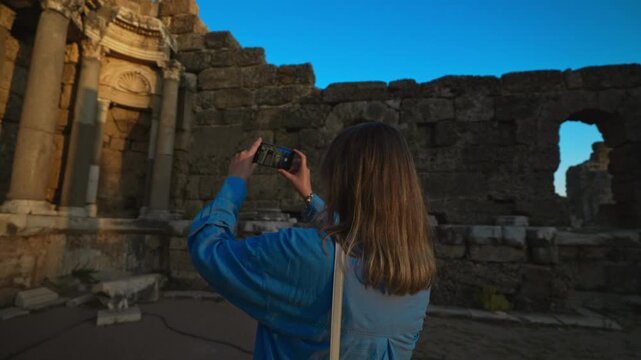 Female tourist takes a photo of the ruins of an ancient city.