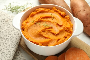 Delicious mashed sweet potatoes in pot and vegetables on table, closeup
